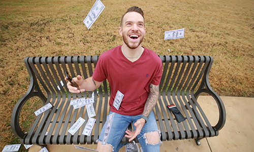 man on bench with money floating around him