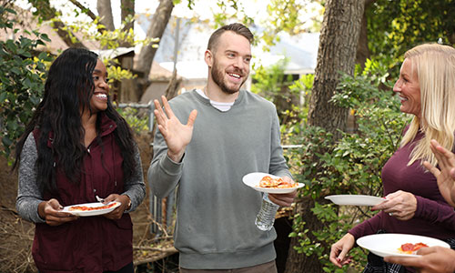 man and two women laughing at cookout